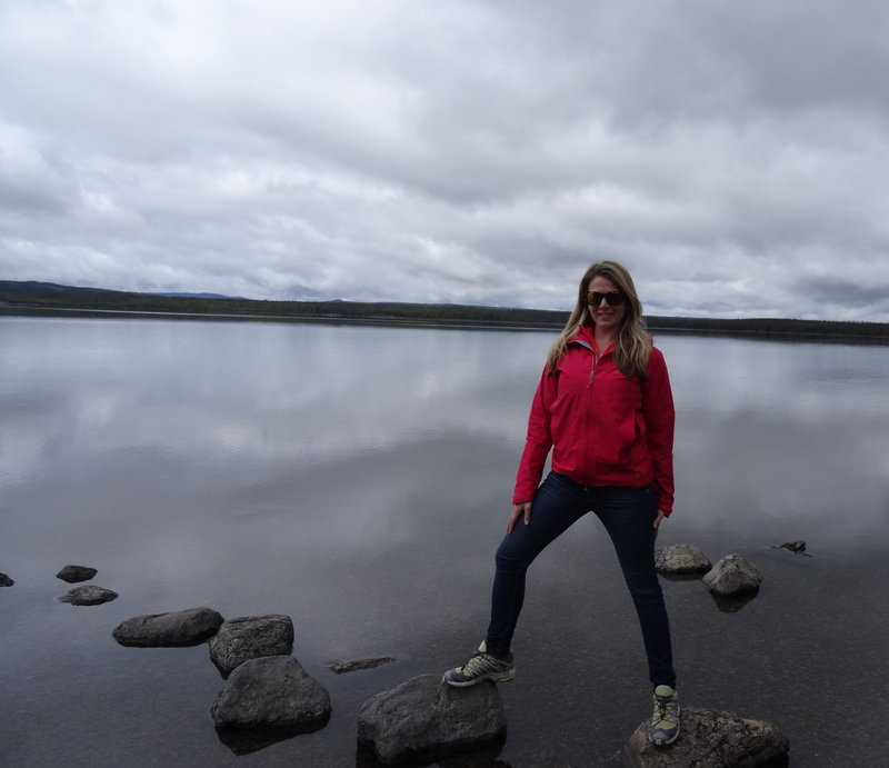 woman standing on rock in front of lake