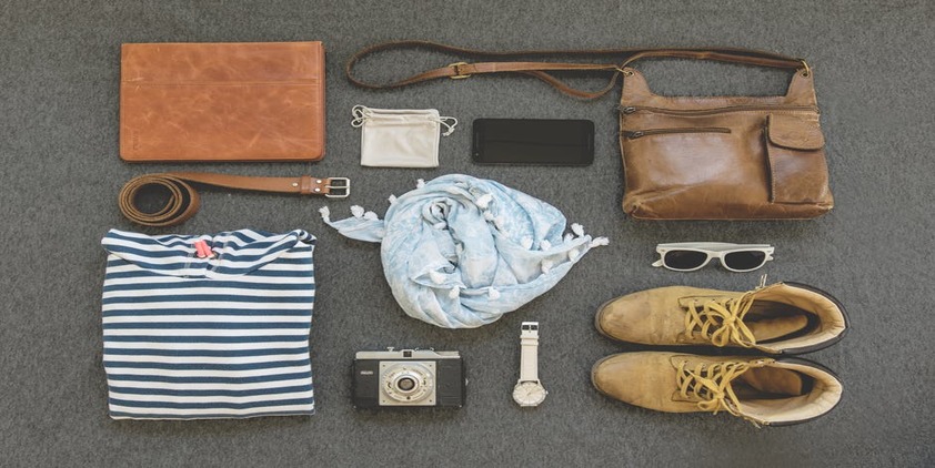 Pexels. Shirt, Purse, Boots, Belt, Sunglasses, Watch, Cell Phone, Camera, and Scarf laid out on a table