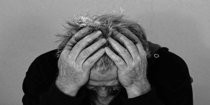 Pixabay. Older man in black and white holding his head