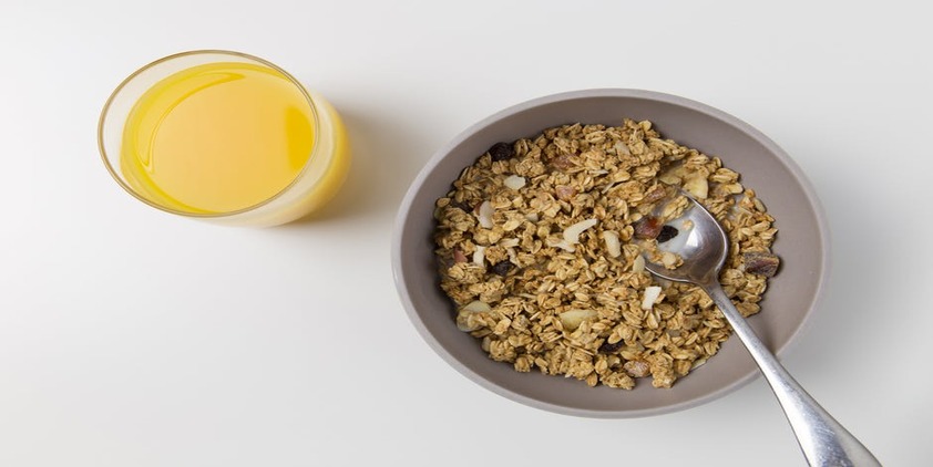 pixels. bowl of oatmeal with dried fruit and orange juice on white table