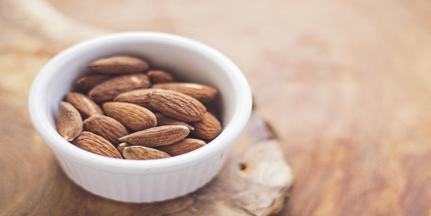 Unsplash. Small bowl of almonds on wooden counter