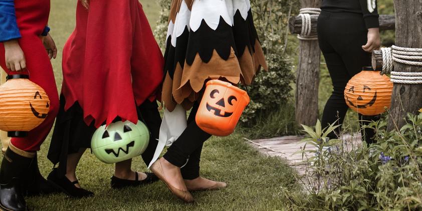 Unsplash. kids dressed up in costumes, going up front porch in halloween costumes with buckets
