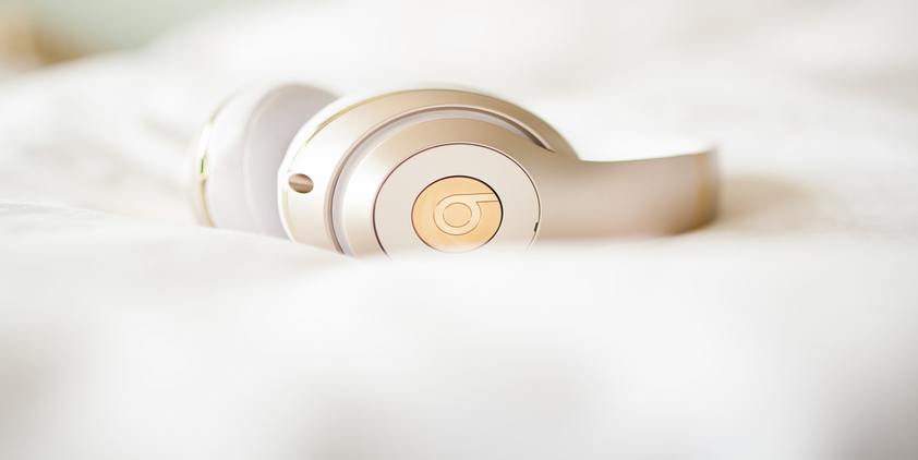 unsplash. beats by Dre headphones on white bed