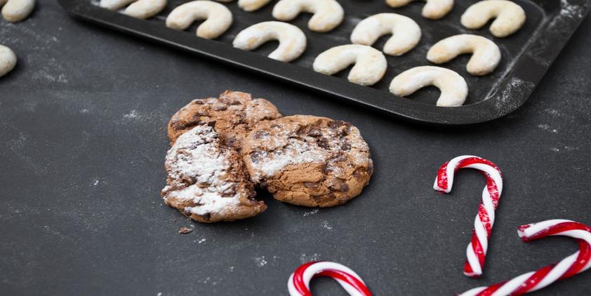 unsplash. chocolate chip cookies with powdered sugar, a candy cane, and cookies on a tray