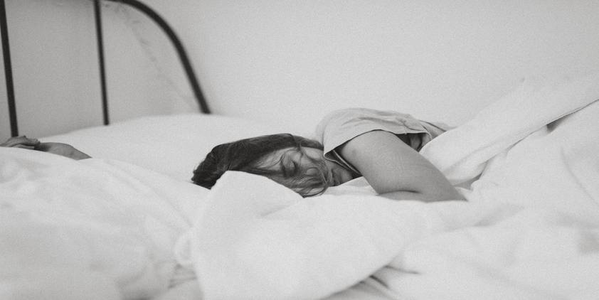 Unsplash. greyscale photo of woman laying in bed on her side