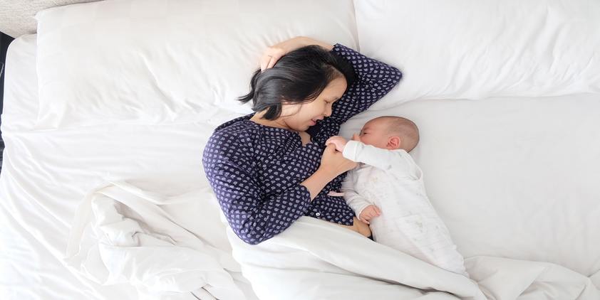 unsplash. woman laying on bed with baby