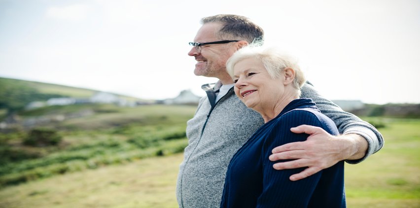 older adults hugging smiling outdoors