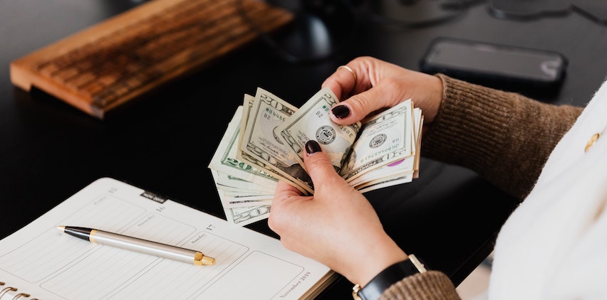 A woman counting cash at her desk