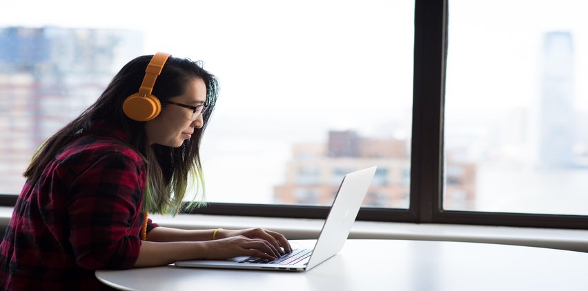 woman listening to headphones while freelancing on computer