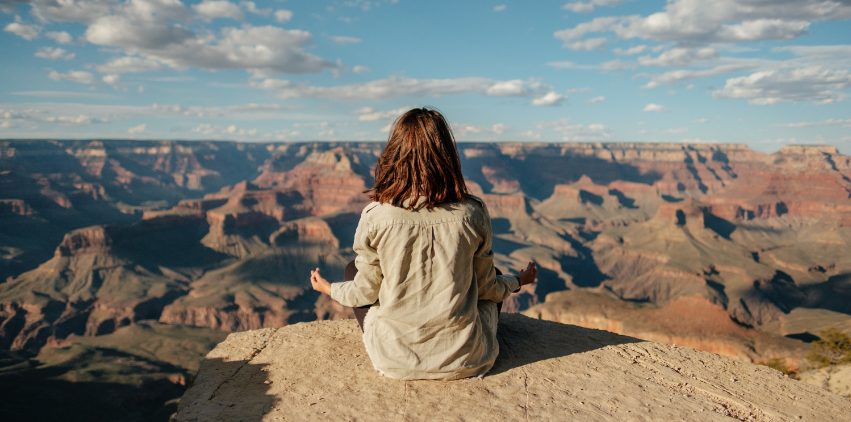 A woman meditates overlooking a canyon