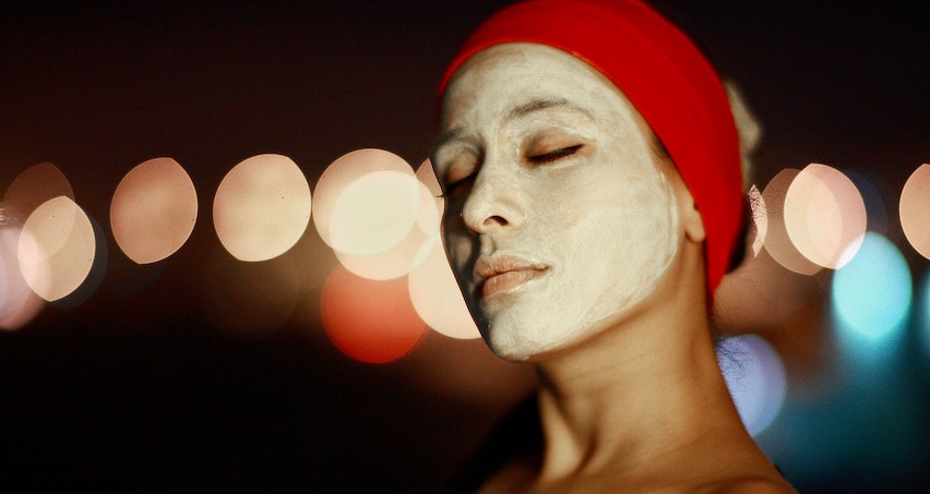 A woman cleans her skin with a face mask