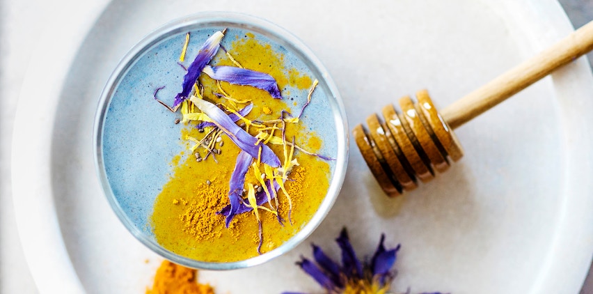 A turmeric latte with honey and edible flowers.