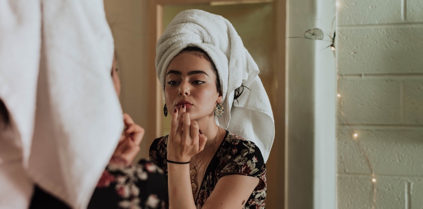 A woman puts on natural beauty products in her bathroom.