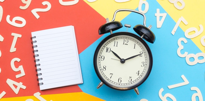 A clock surrounded by letters and a blank notebook.