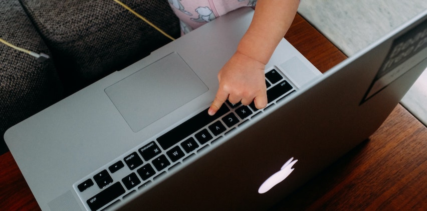 A baby touching keys on a laptop