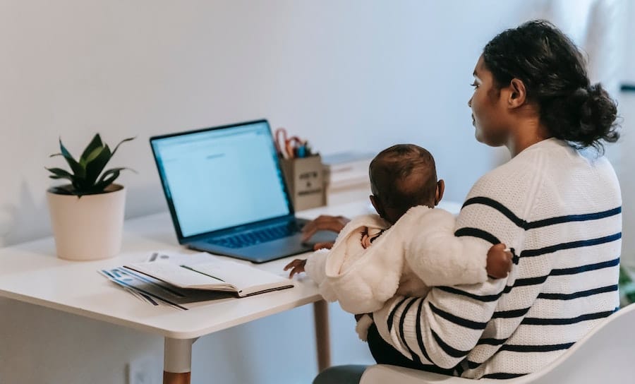 woman working at computer holding baby in lap