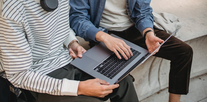 Two people sitting with a laptop.