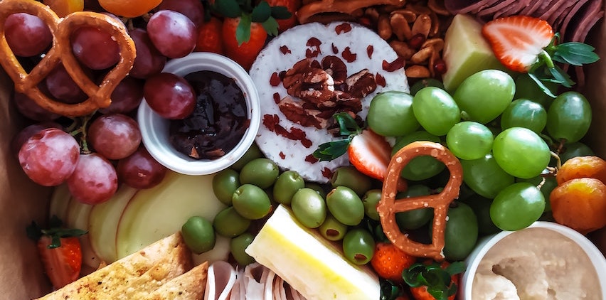 Charcuterie board with fruit, pretzels, and cheese