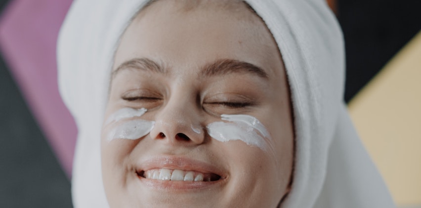 a woman smiling with under-eye cream