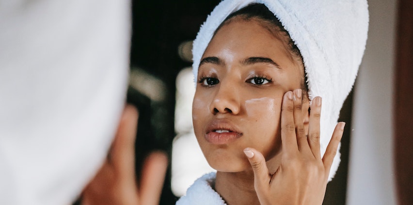 A woman applying a moisturizer to her face