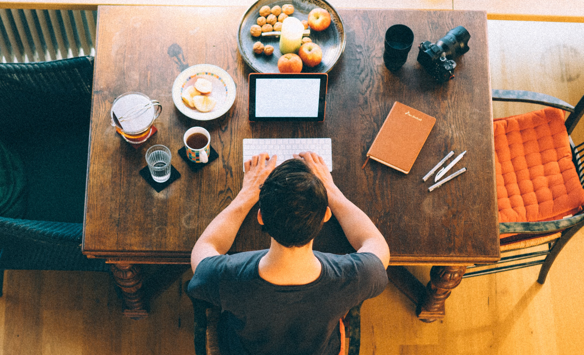 A man working at a kitchen table in the morning.