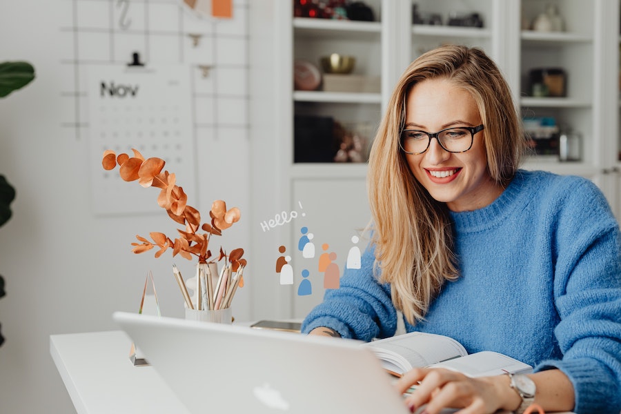 woman working on a laptop wearing a blue sweater